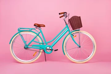 Zelfklevend Fotobehang Foto van vrouw retro vintage fiets gebruikt voor stadsvervoer met bruine mand geïsoleerd over roze kleur achtergrond © deagreez