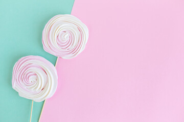 Two meringues on pink and turquoise background. Concept for holiday greeting card or background.