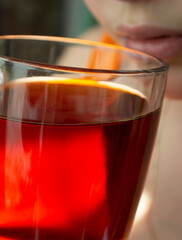a photo of a girl drinking black tea from a transparent large mug. Close up