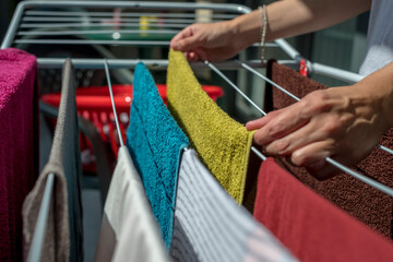 hands of a woman hanging clothes and towels on an outdoor clothesline to dry in the sun