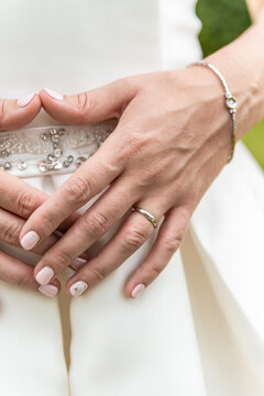 Bride in wedding dress, close-up photo of hand and wedding ring.
