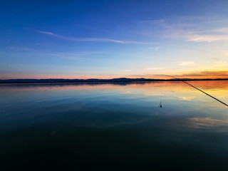 Sunset on the lake. Fishing rod in the foreground. Poland.