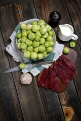 Raw Brussels sprouts, beef jerky, pepper and cream in rustic style