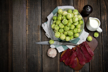 Raw Brussels sprouts, beef jerky, pepper and cream in rustic style