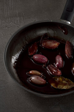 karamellisierte Rotwein Schalotten in Pfanne auf dunklem Stein Tisch
