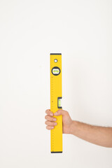Close-up of unrecognizable repairman holding yellow construction level against isolated background