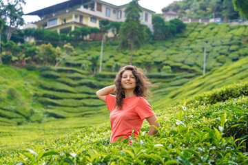 Beautiful brunette girl posing in the middle of the tea valley between green tea bushes.