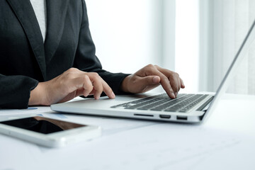 The hands of a male businesswoman are analyzing and calculating the annual income and expenses in a financial graph that shows results To summarize balances overall in office