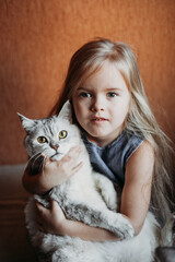a girl with blond hair holds a cat , a pet, and a house