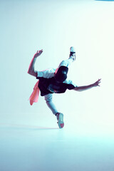 Fototapeta na wymiar Young guy breakdancer performs trick in jump dancing in studio in neon light. Break dance lessons. Dance school poster
