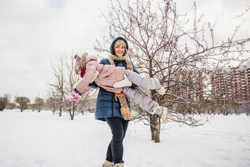 mother and daughter walk in the Park in the city with a dog in winter, entertainment and fun, warm clothes and snow