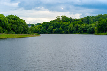 Calm pond in green countryside. Above amazing lake with tranquil water located near green forest in nature