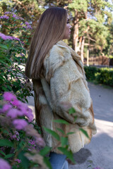 a beautiful girl with long hair and expressive eyes poses in a fur coat in a Park. High quality photo