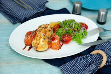 Fish cakes with salad, tomatoes and red onions in a restaurant on a white plate. Red salmon fish. Fish menu. Close-up. Healthy Omega-3 food on blue table background.