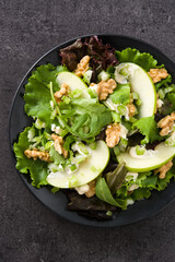 Fresh Waldorf salad with lettuce, green apples, walnuts and celery on black stone. Top view	