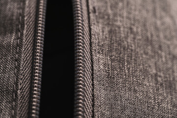 Closeup vertical open zippers of gray cloth bag in low light mood