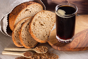 Kvass with rye bread and whole grain in wooden spoons on wooden background. Top view.