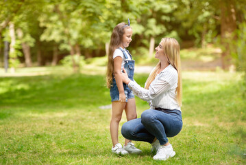 Fototapeta premium Happy Mother And Little Daughter Talking Walking In Park Outdoors