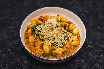 plant-based food, vegan potato gnocchi with sundried tomatoes and peas in red pesto sauce with dairy-free cheese