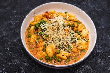 plant-based food, vegan potato gnocchi with sundried tomatoes and peas in red pesto sauce with dairy-free cheese