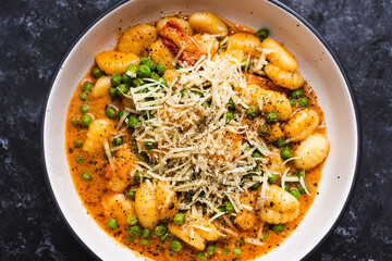 plant-based food, vegan potato gnocchi with sundried tomatoes and peas in red pesto sauce with dairy-free cheese
