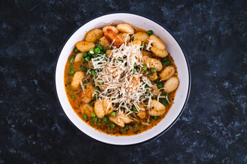 plant-based food, vegan potato gnocchi with sundried tomatoes and peas in red pesto sauce with dairy-free cheese