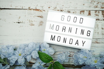 Good Morning Monday word in light box with Flowers Decoration on wooden background