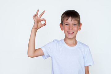 Portrait of cute Caucasian boy showing ok gesture, success, agreement on white background. Successful study concept