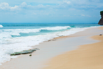 An ideal tropical sandy beach for surfing on the ocean. Beautiful clear turquoise water and waves.