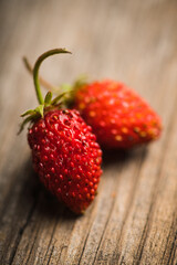 Freshly harvested wild strawberry on the rustic wooden background. Selective focus. Shallow depth of field.