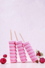 Three raspberry ice cream popsicles on the white table. Copy space
