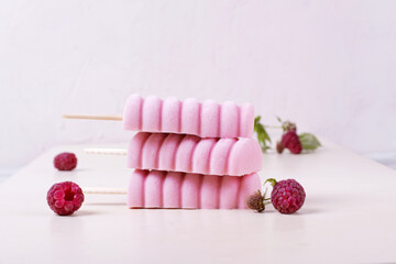 Three raspberry ice cream popsicles on the white table. Copy space
