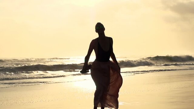 Happy woman turning around on beach during sunset