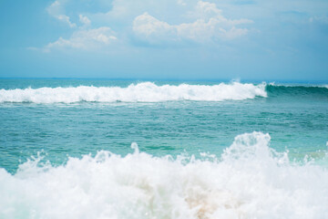 An ideal tropical sandy beach for surfing on the ocean. Beautiful clear turquoise water and waves.