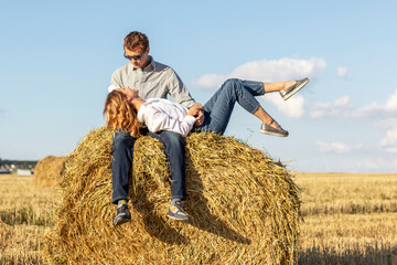 Outdoor portrait of couple in love sitting on hay bale. © Serhii