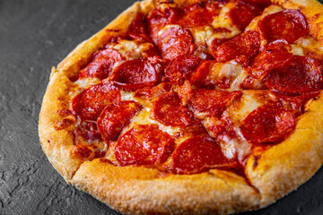 Pepperoni Pizza with Mozzarella cheese, salami, Tomato sauce, pepper, Spices. Italian pizza on Dark grey black slate background
