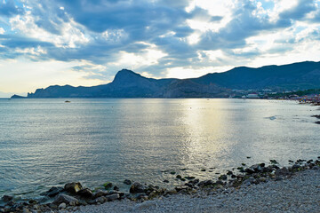 View of the sea and mountains from the shore at sunset