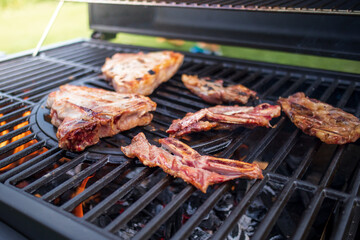 Home barbecue with charcoal in the backyard grilling steaks and other meats for carnivore diet.