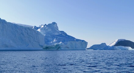 Fototapeta na wymiar Blue iceberg in antarctic ocean, blue sky and sun, melting ice, Antarctica