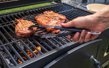 Home barbecue with charcoal in the backyard grilling steaks and other meats for carnivore diet.