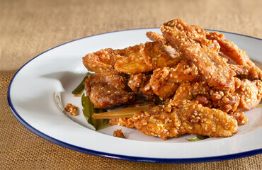 Fried banana mix sesame and pandan leaf for aroma (Thai called Kluay kack) in white dish and on light brown tablecloth Thai snack