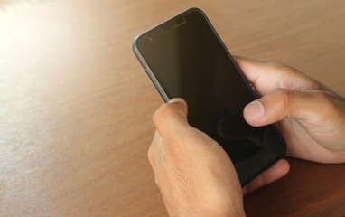 men's hands are holding a smartphone on the desk