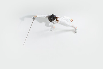 First. Teen girl in fencing costume with sword in hand on white background. Top view. Young female...