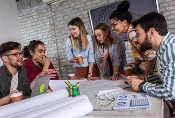 Group of modern business people in casual wear discussing architectural design in the creative office.