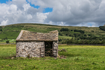 Old barn in the field with blue sky and clouds