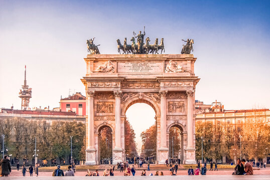 The Arch of Peace (Arco della Pace) in Piazza Sempione, Milan, at sunset, with people. Designed in neoclassical style by Luigi Cagnola in 19th century