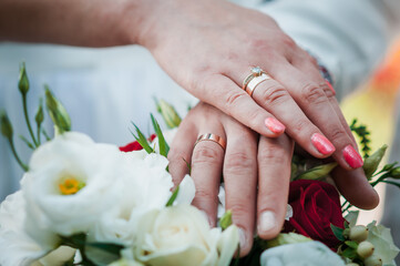 Obraz na płótnie Canvas hands of newlyweds with wedding rings on wedding bouquet