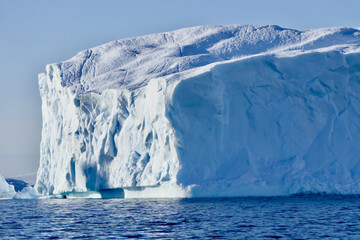 Blue iceberg in antarctic ocean, blue sky and sun, melting ice, Antarctica