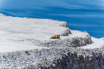Aerial view of opencast mining quarry with one machinery on the blue sea background