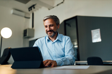 Portrait of a smiling businessman using digital tablet.
